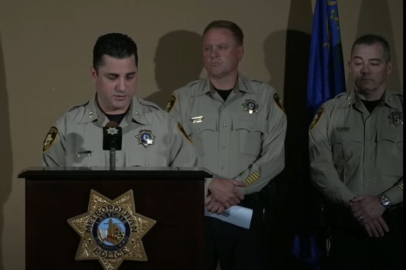 Two police officers stand at a podium.