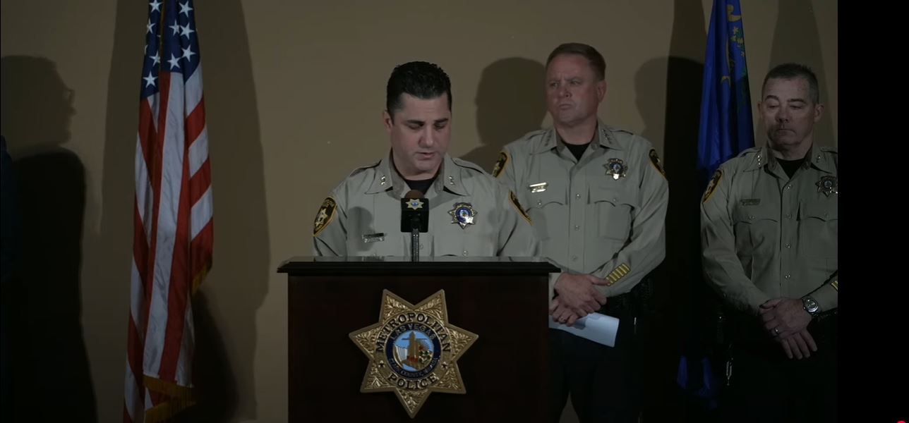 Two police officers stand at a podium.