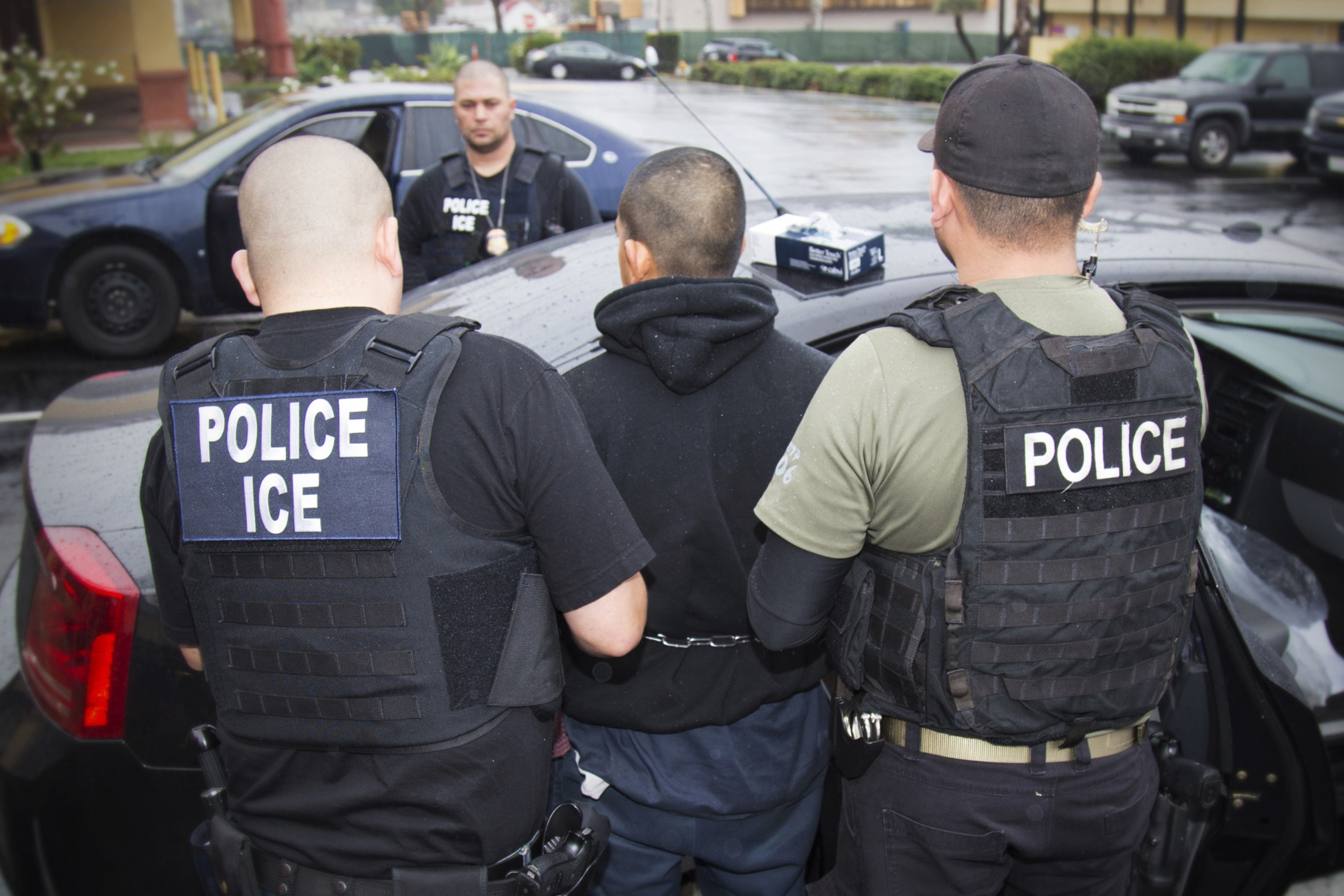 Three men arrest a man and place him in a vehicle