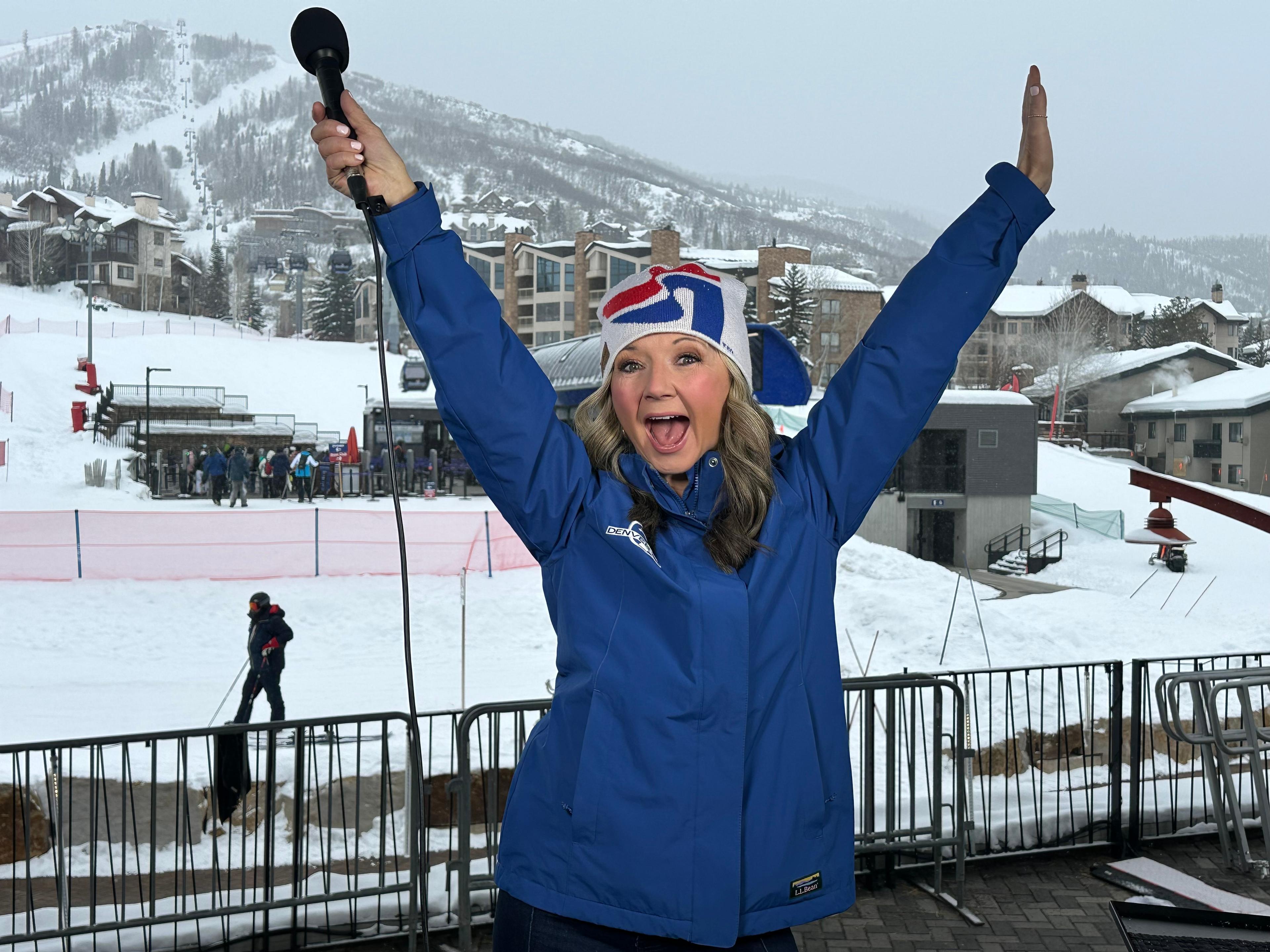 Denver7 chief meteorologist Lisa Hidalgo is seen with her arms raised above her in a fun, happy expression of joy in Steamboat Springs.