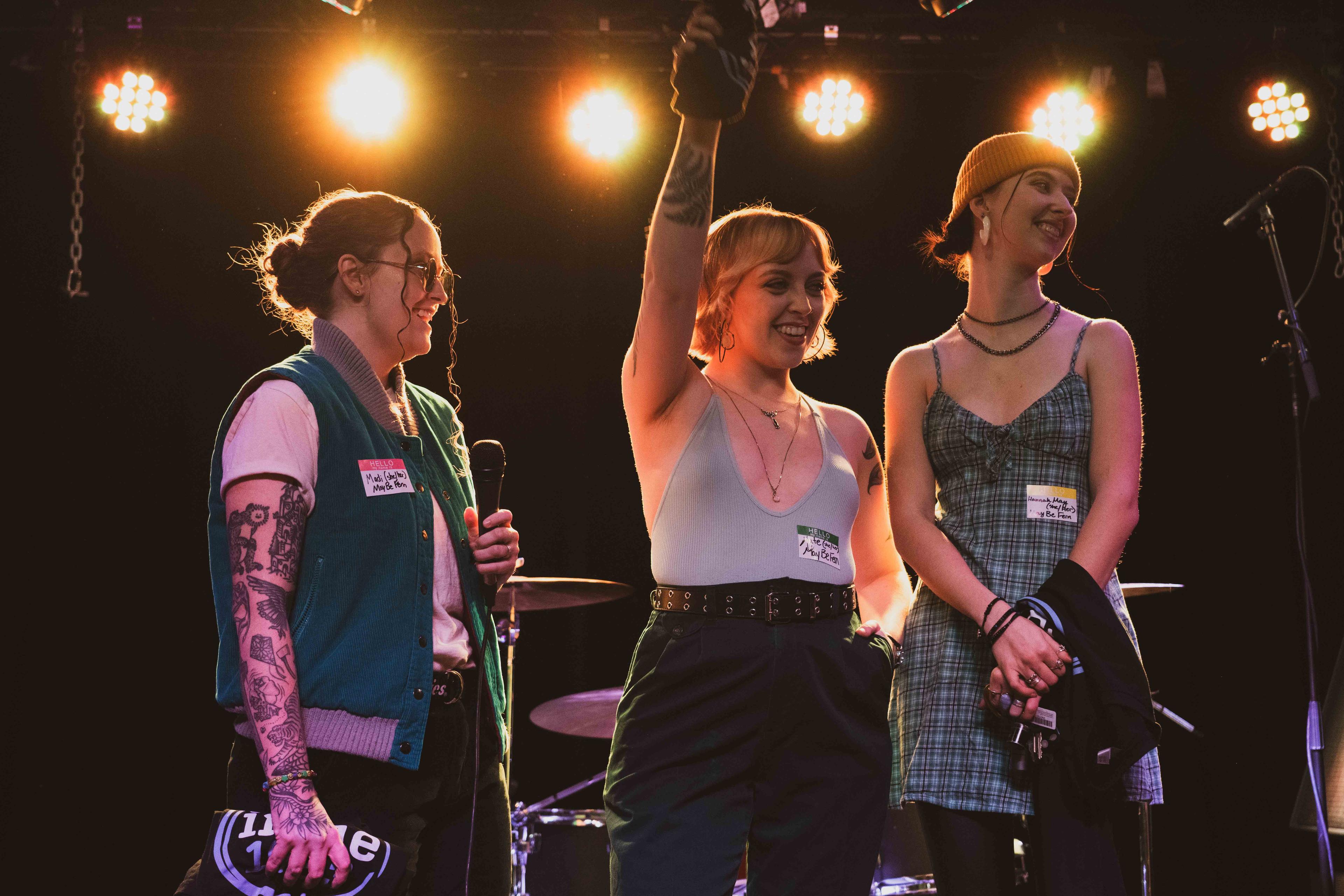 The three members of May Be Fern celebrate their first-place finish on stage