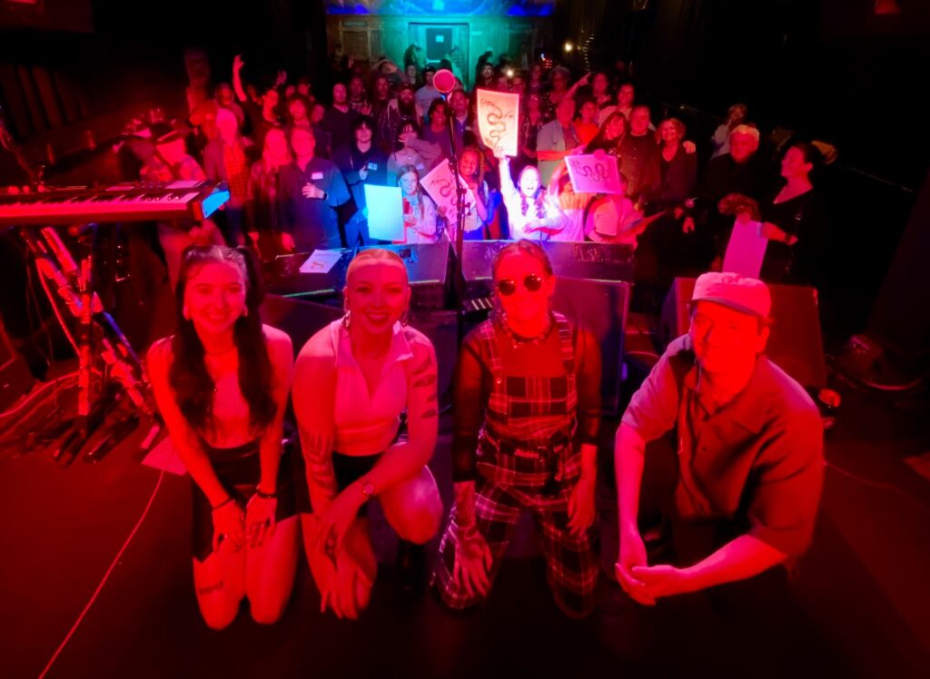 Attendees bathed in red light pose in front of the stage at the Local 303 Meetup with May Be Fern at Globe Hall, November 2024