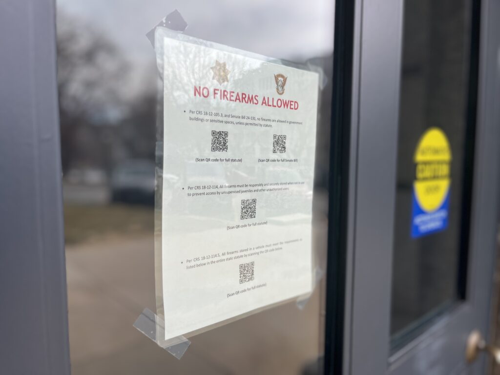 A flier taped to a glass door at the state Capitol warns those entering that no guns are allowed in the building except for law enforcement.