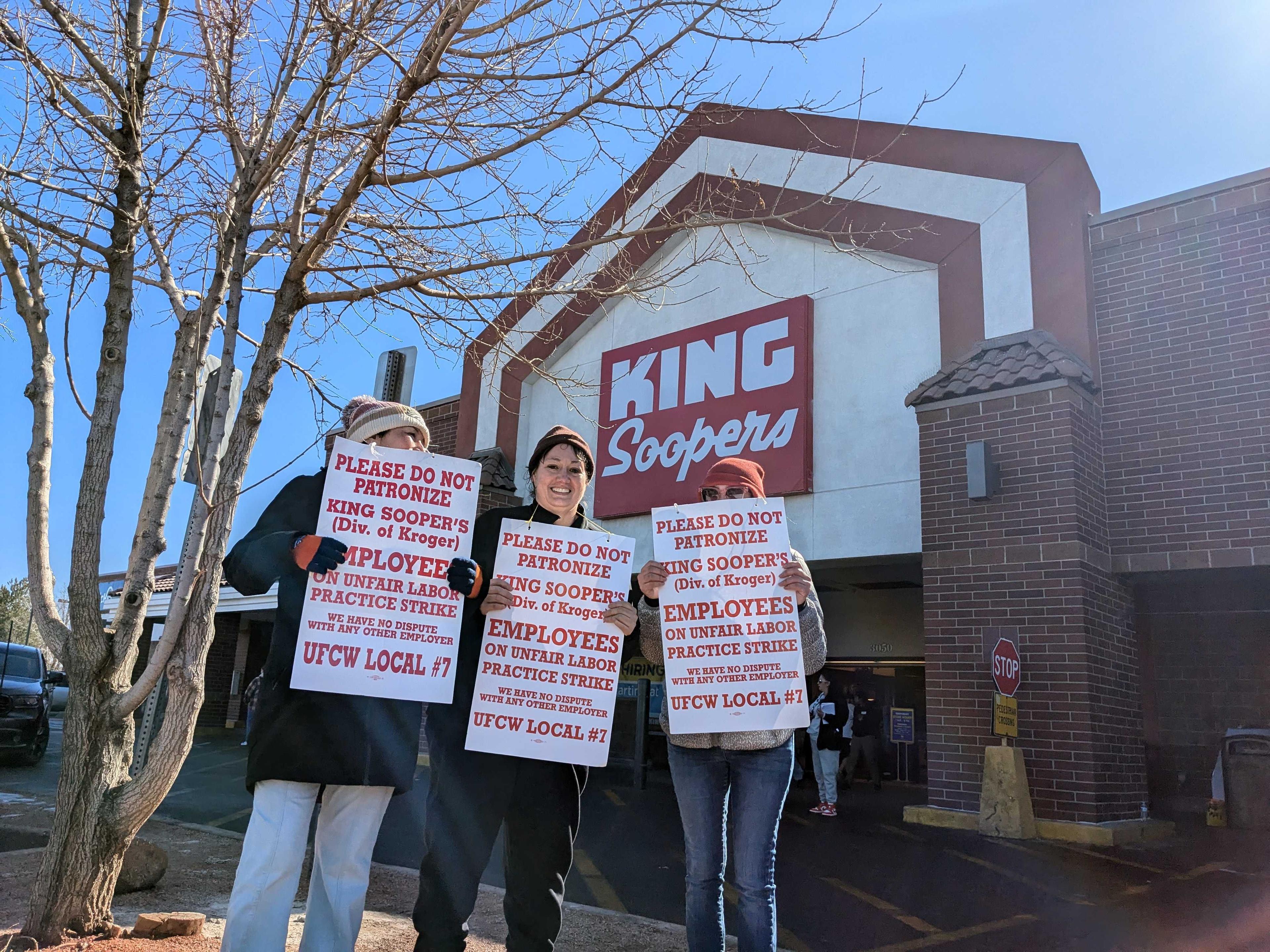 People outside King Soopers grocery store display picket signs