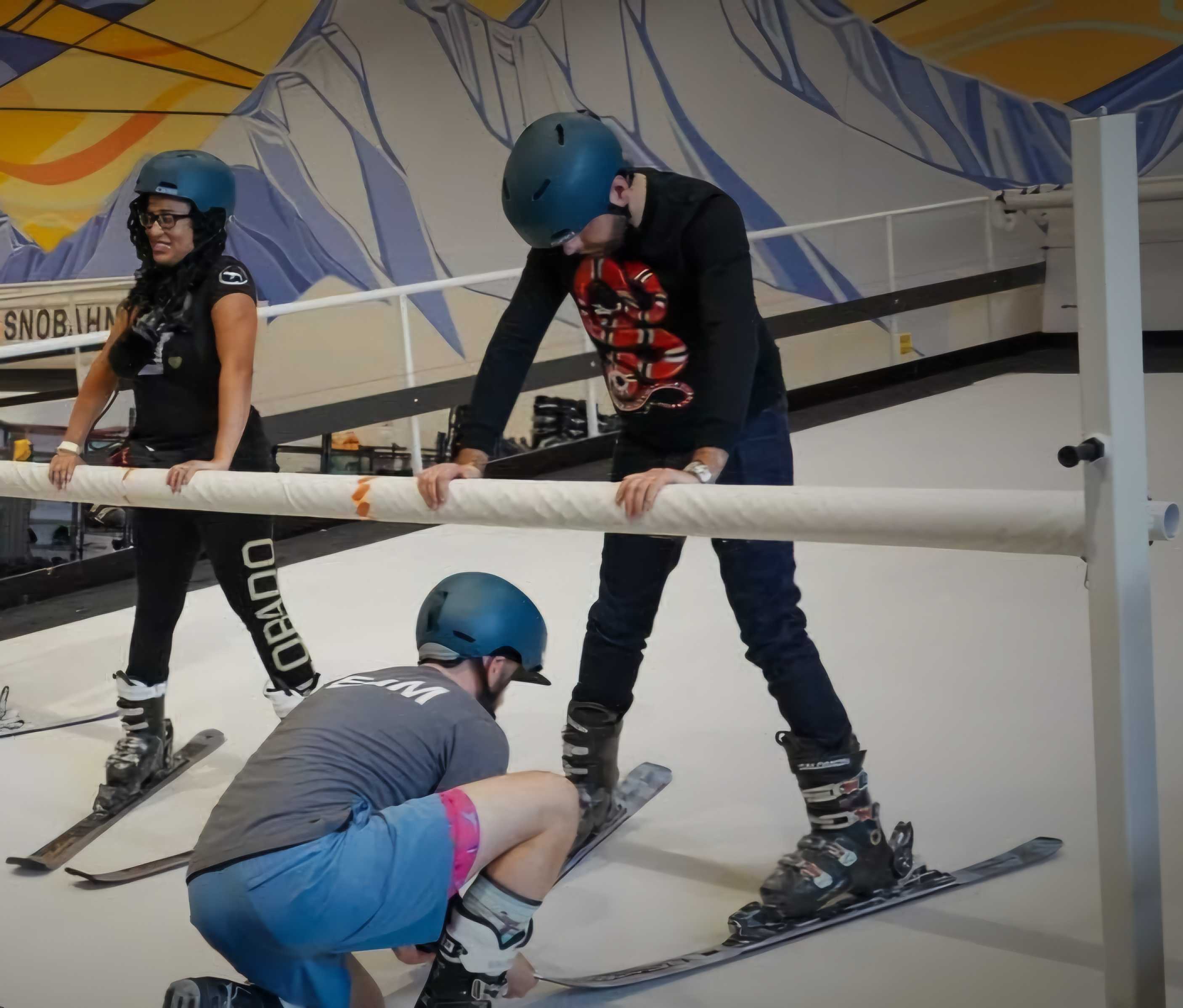 Colorado Matters host Chandra Thomas Whitfield is seen holding a horizontal support bar on an indoor ski slope as she learns to stabilize herself on skis.