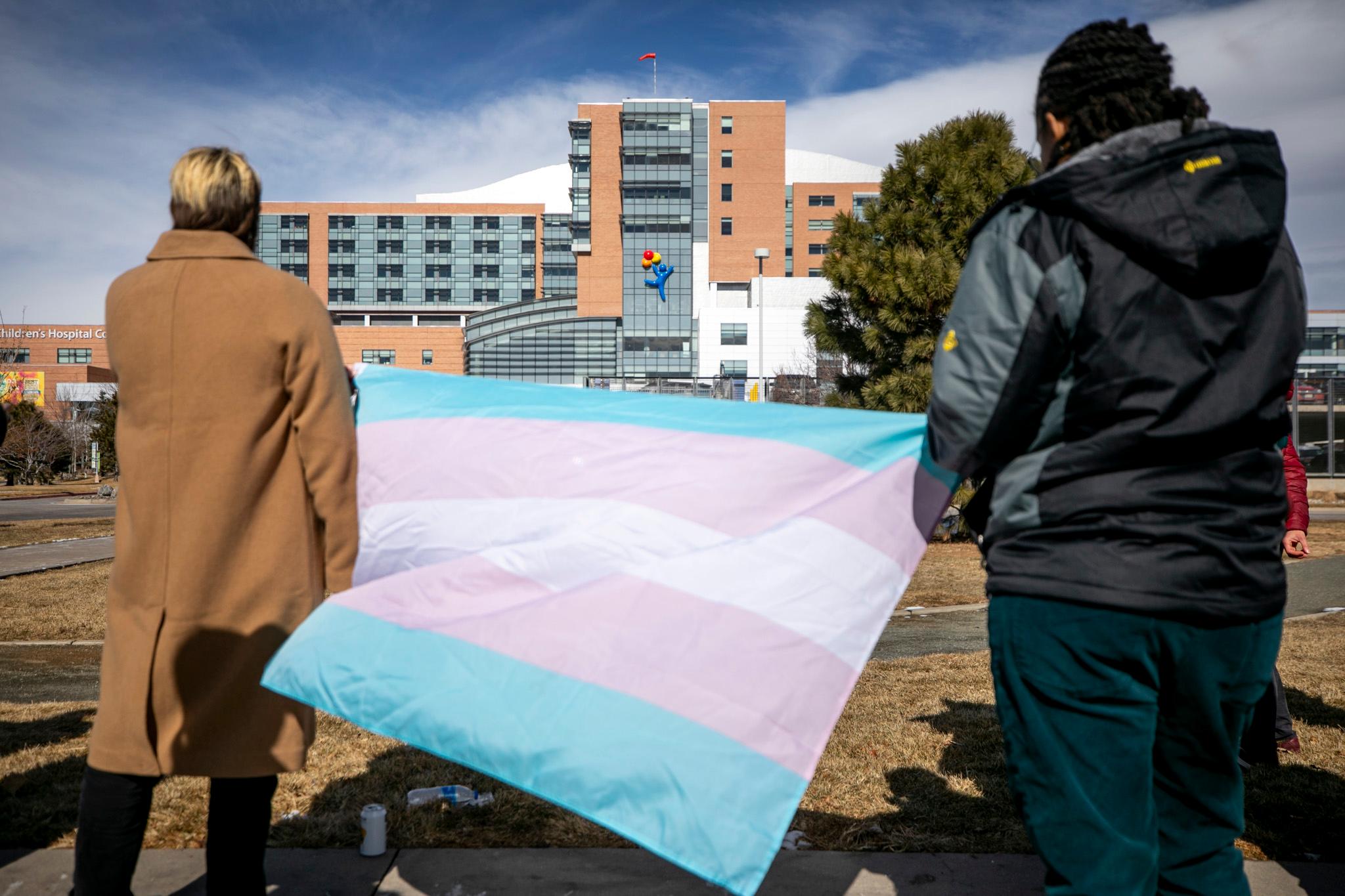 Protestors hold a trans flag outside Children's Hospital