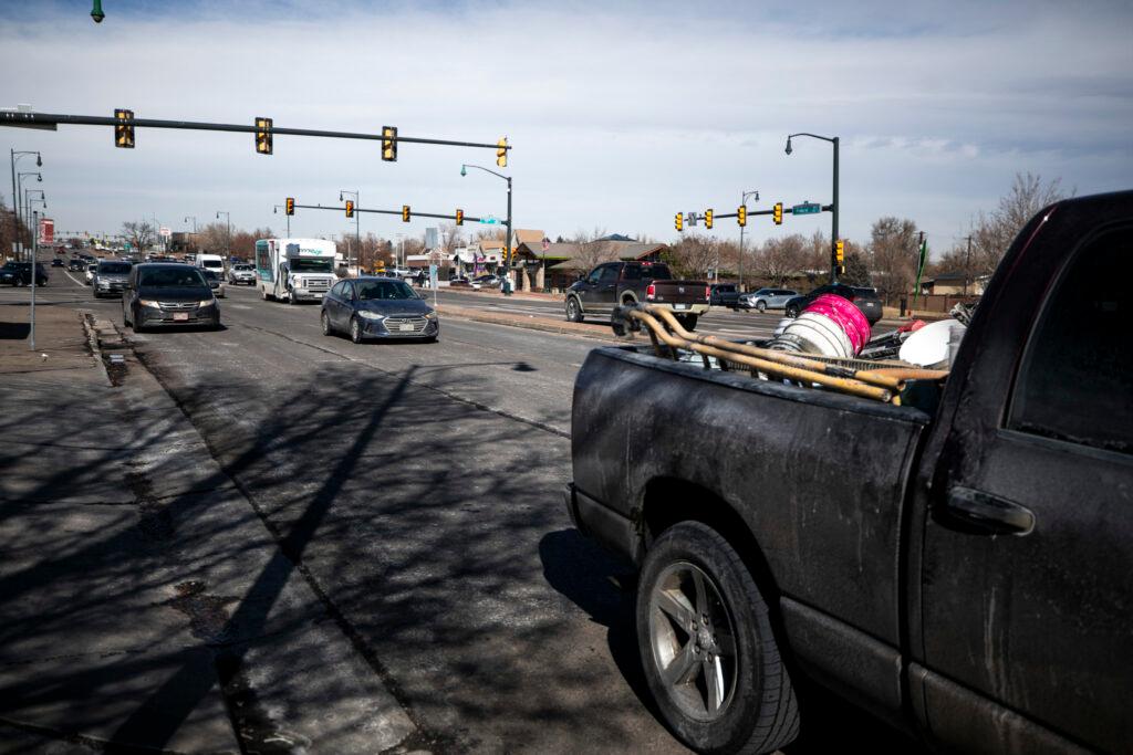 A street with cars on it passing under a traffic light.