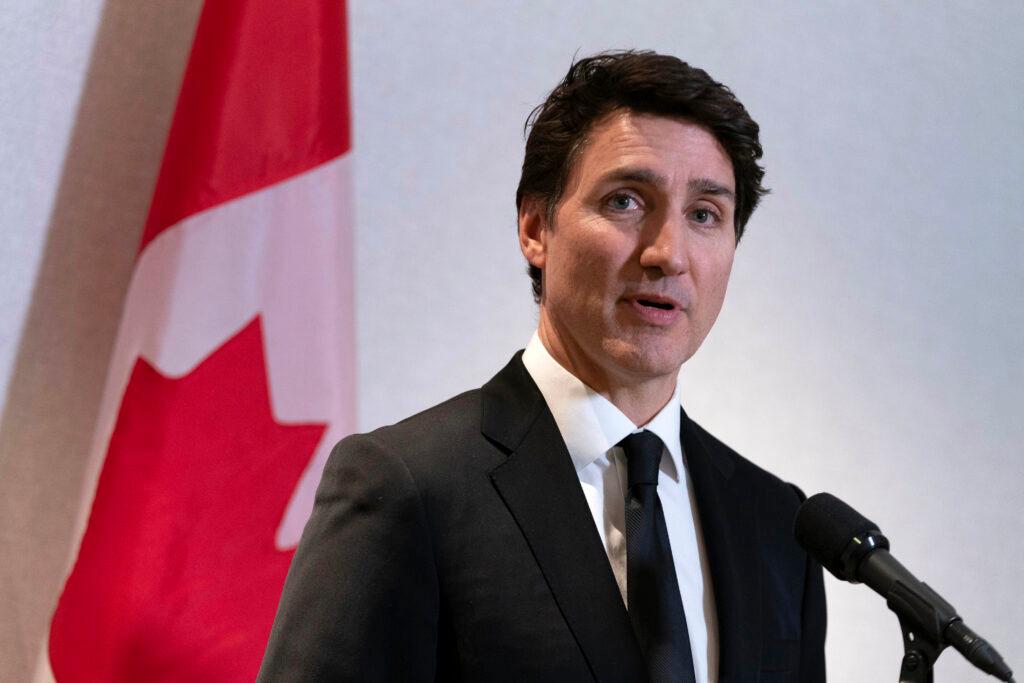 Justin Trudeau stands in front of a Canadian flag