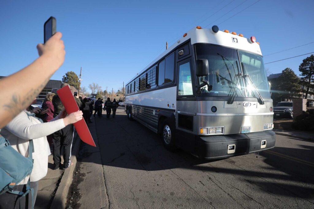 People protest a bus passing by during an immigration raid