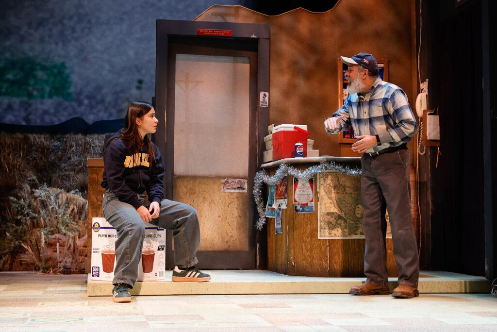 On stage, Mayelah Barrera and Bobby Plasencia portray Mia and Moises, seated together on a bench in &quot;In Her Bones.&quot;