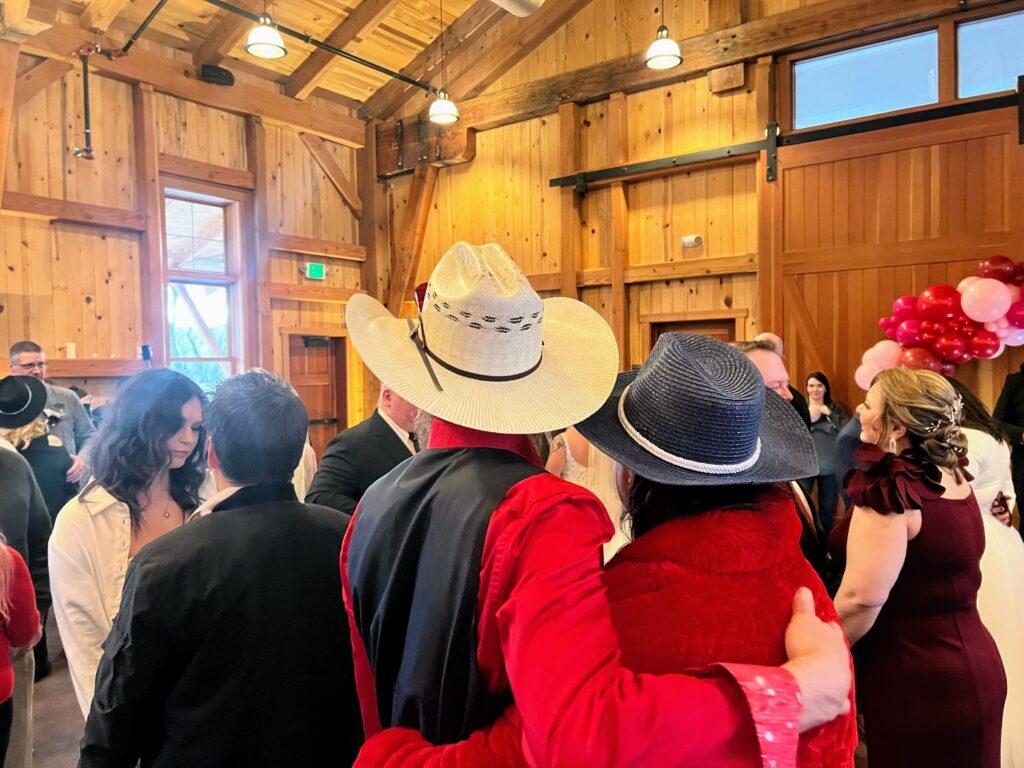 A couple embraces, wearing big cowboy hats, on their wedding day.