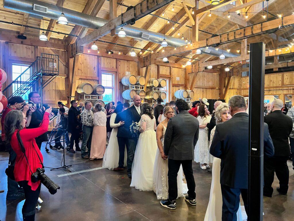 Couples gather for the group wedding in large rustic barn.