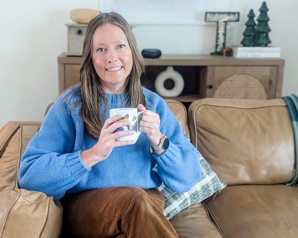 A woman sits with coffee.