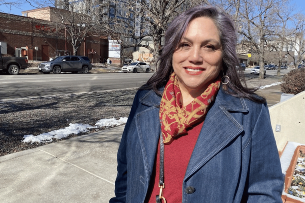 A woman stands on a sidewalk for a photo