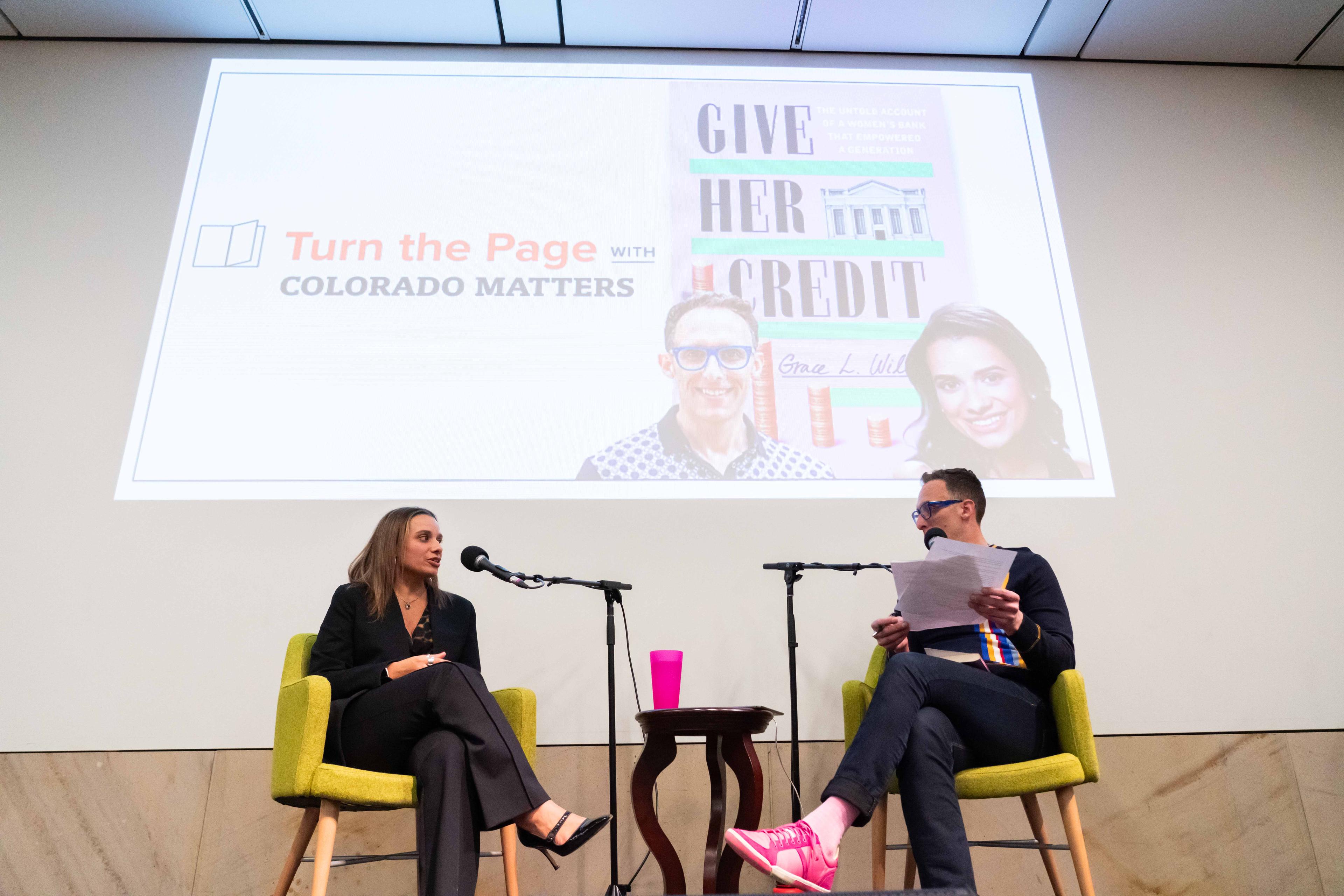 Author and host on stage together at History Colorado Center. Projection of book cover in background.