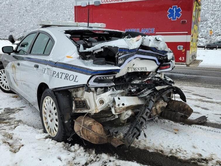 a damaged state patrol car and an ambulance in the background in a snowy setting