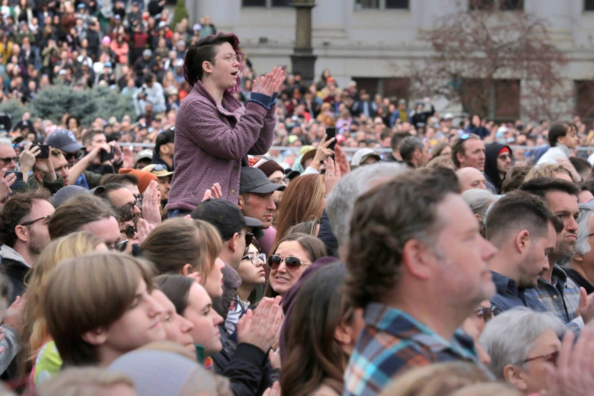 A person in a fuzzy purple jackets stands taller than the large crowd.