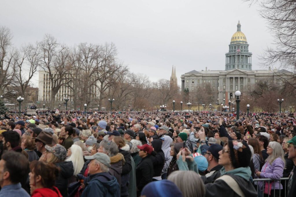 A large crowd watches a political rally with the state Capitol in the background.