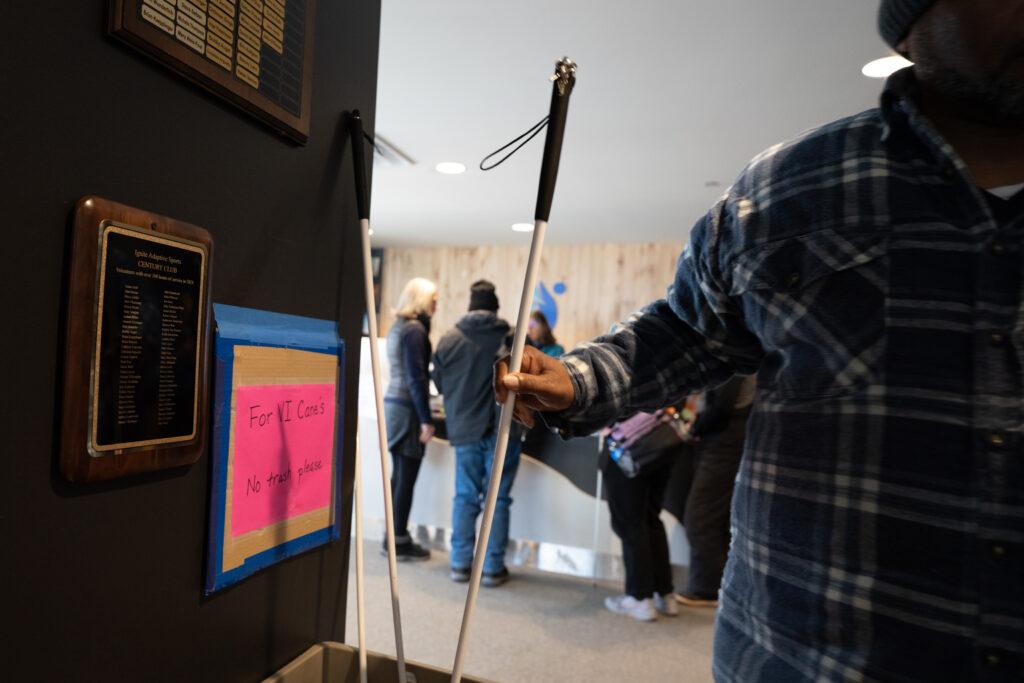 A visually impaired ignite athlete deposits his cane in a designated container at the organization’s check-in area