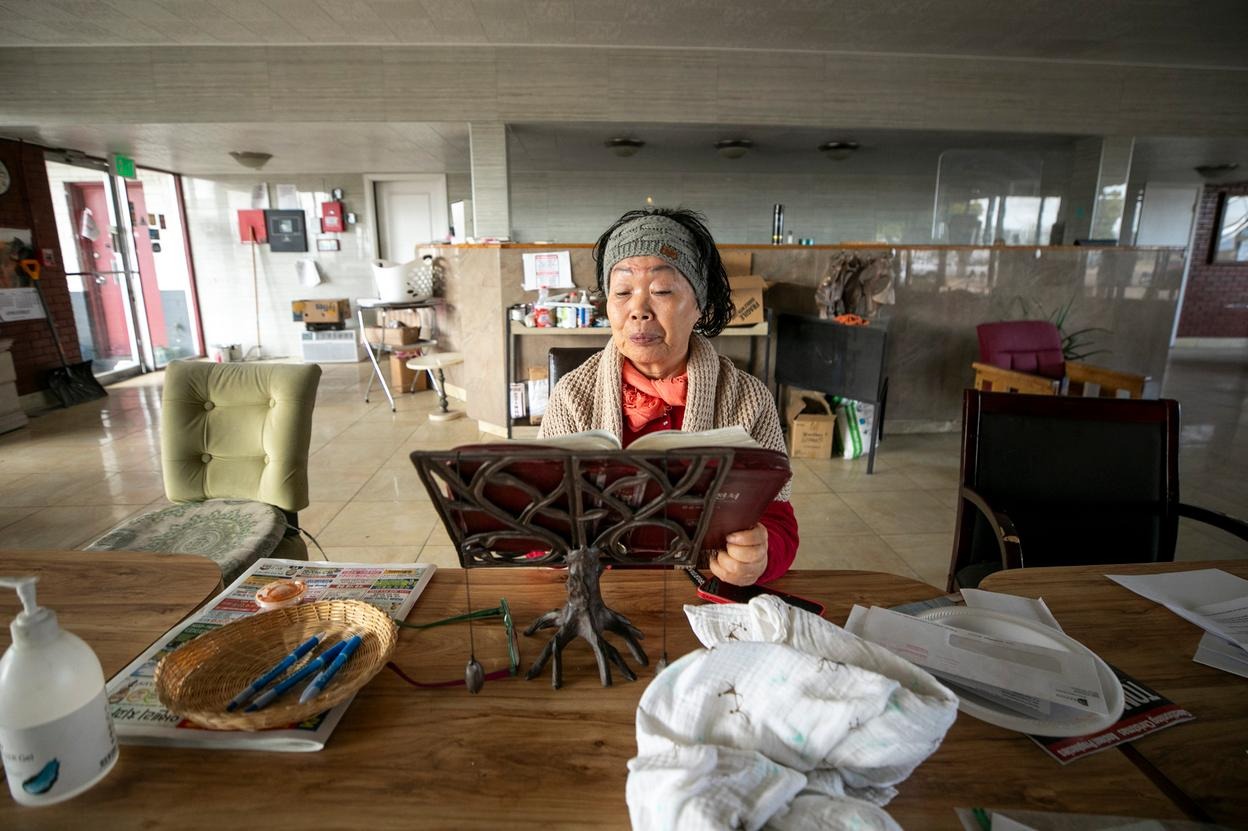 Yong Cha Prince reads a Korean Bible in her Western Motor Inn.