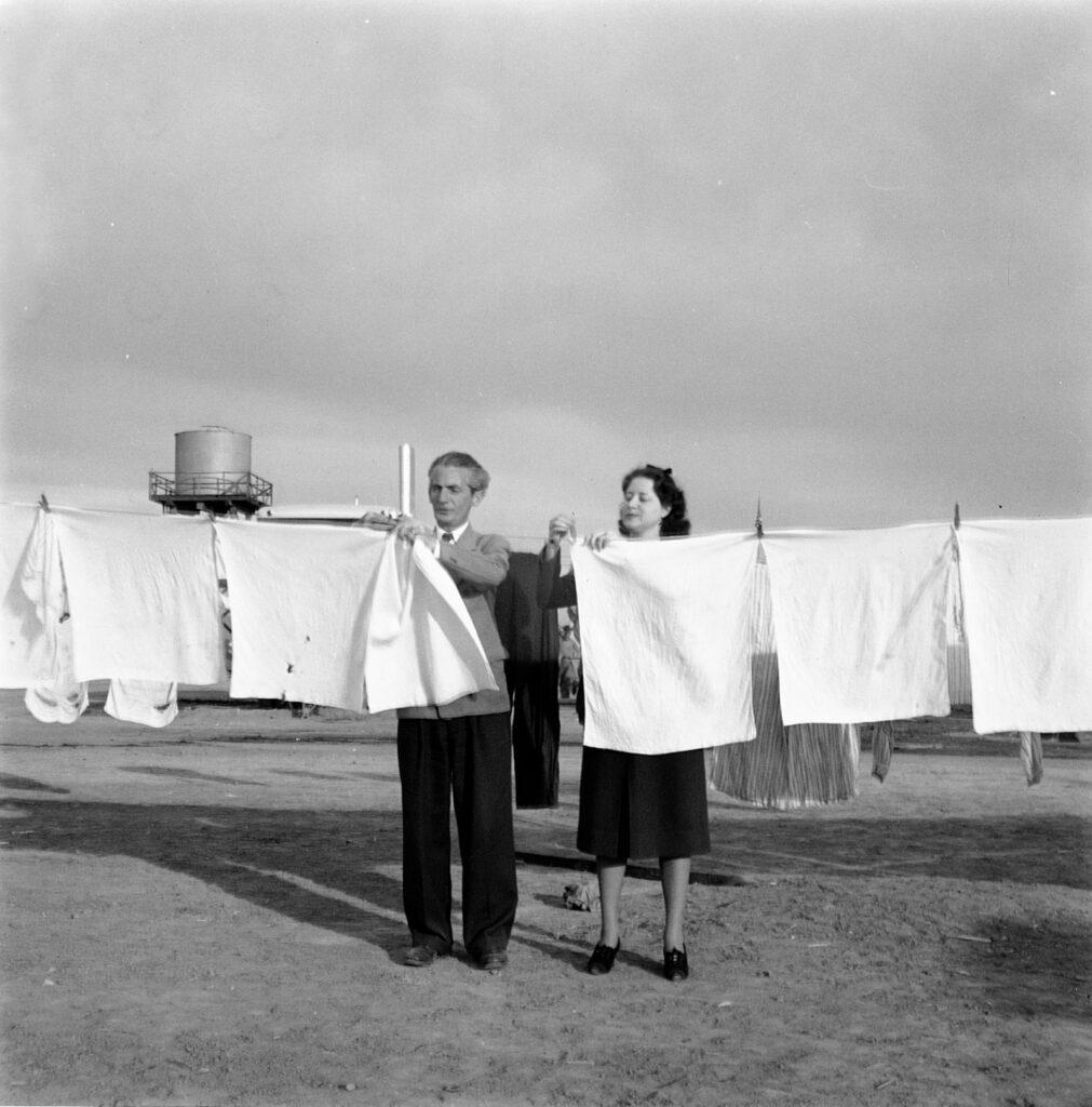 black and white photo of two people hanging laundry on a clothes line