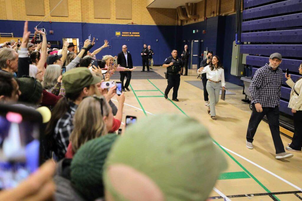 Alexandria Ocasio-Cortez walks into the Bank of Colorado Arena in Greeley, taking her phone out to shoot a photo or video of the excited crowd as she enters the building.