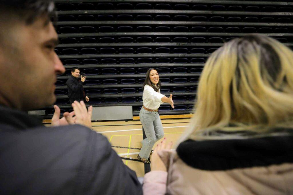 Alexandria Ocasio-Cortez reaches out towards the crowd, as if she's about to shake someone's hand