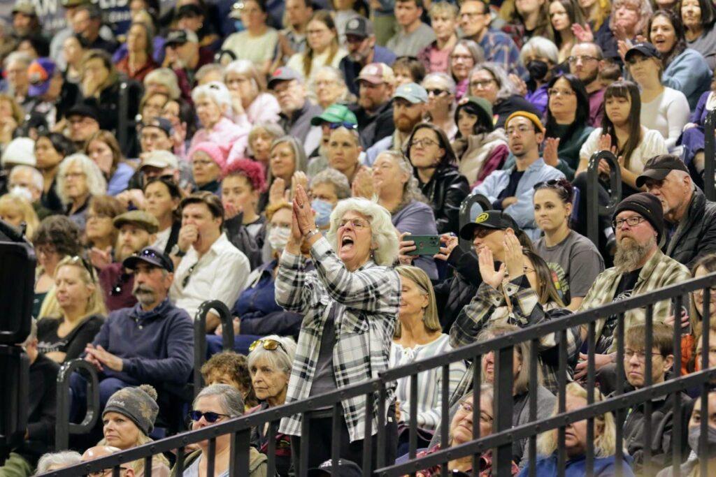 A woman in the crowd stands to clap and cheer