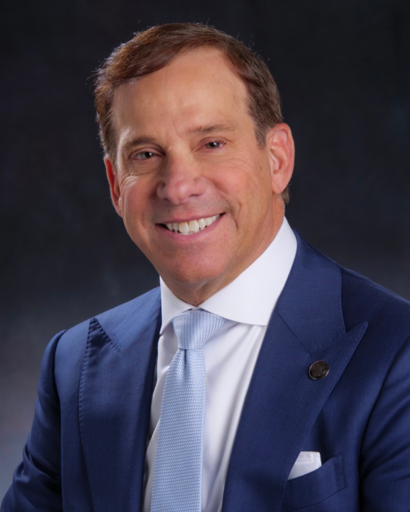 middle age man smiling wearing blue suit, white shirt and blue tie