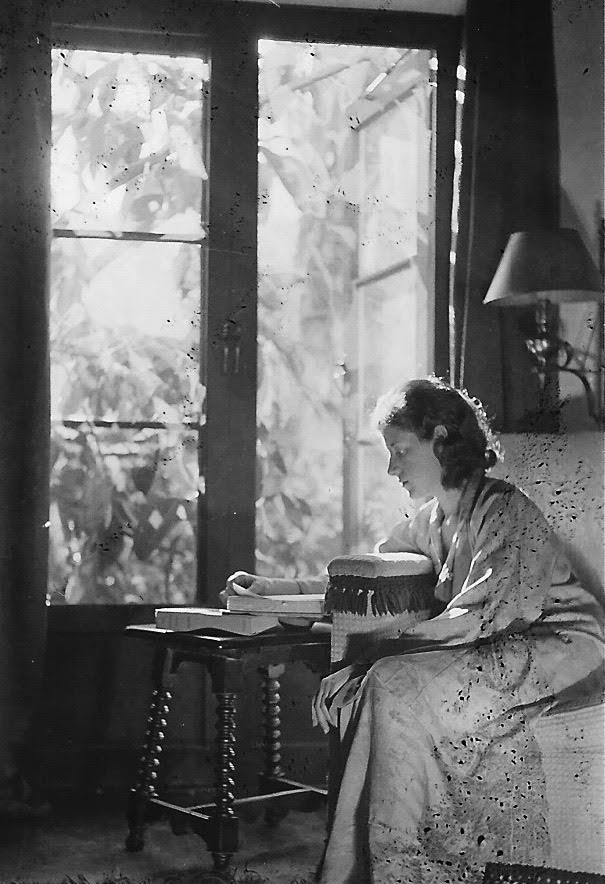 a woman reads by a window in a black and white photo