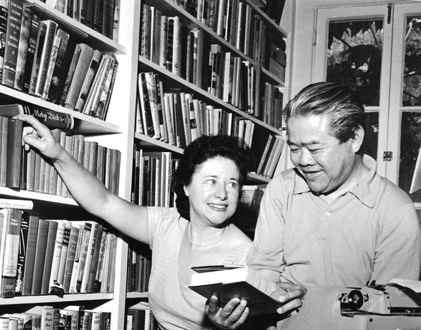 A black and white photo of people at a large bookcase