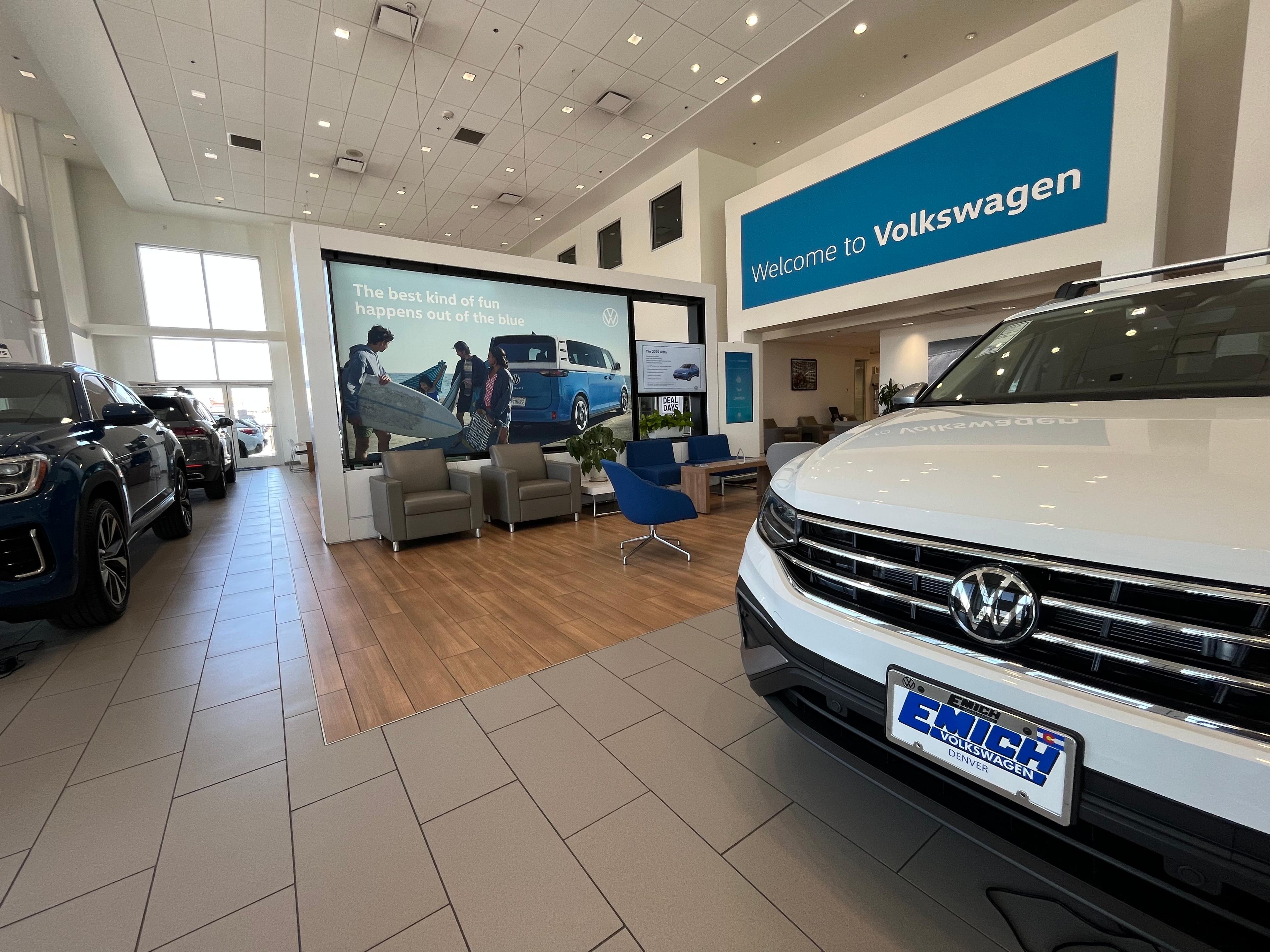 A white SUV sits in a car showroom with a Welcome to Volkswagen sign in the background.